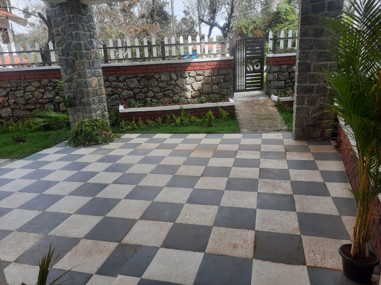 Checkered parking porch and stone pillars at Kodai Vellapar